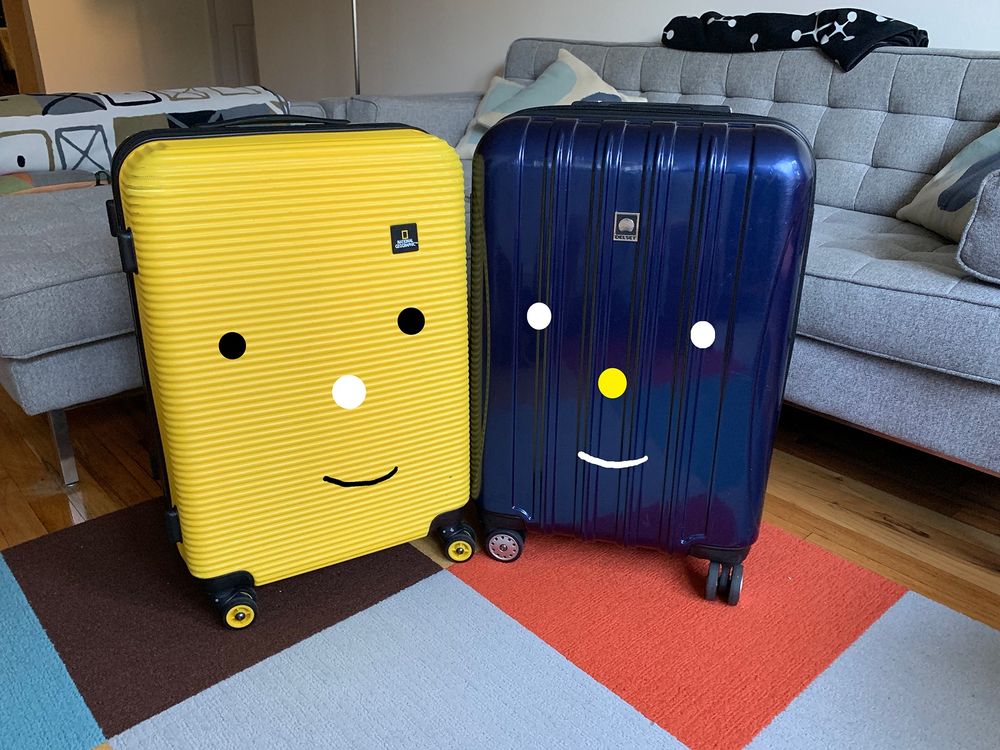 Two rolling suitcases smiling together 