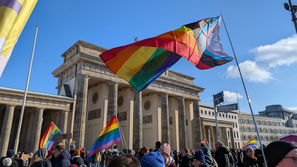 Die Demonstration lief auch am Brandenburger Tor vorbei. Das ist im Hintergrund zu sehen, davor eine Regenbogen-Fahne.