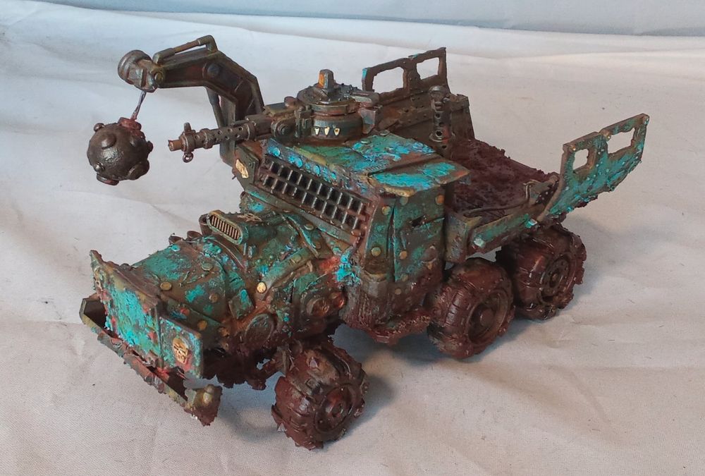 A kitbashed Ork Trukk, of the Deathskull clan. It has an enclosed cab, and looks very dirty. Side angled view.