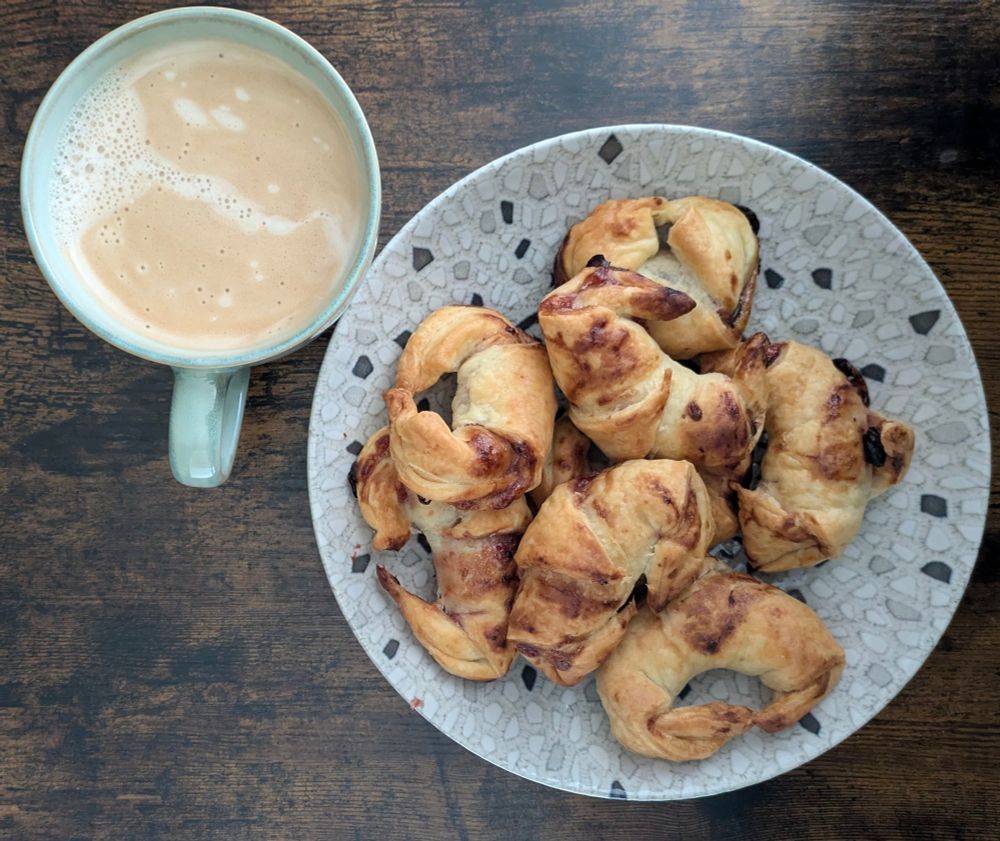 Café con minicruasanes rellenos de mermelada de frutos rojos recién sacados del horno. 
