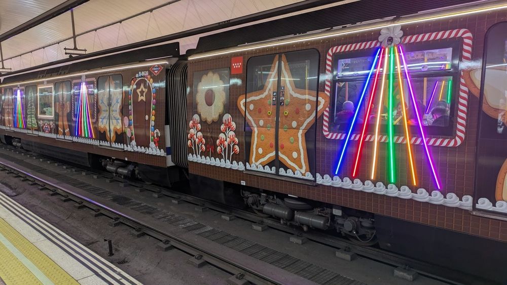 Fotografía de vagones de Metro decorados con motivos navideños por fuera. 