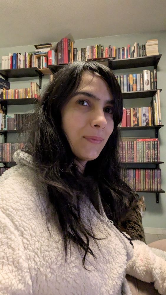 Foto mía con la biblioteca de casa detrás.