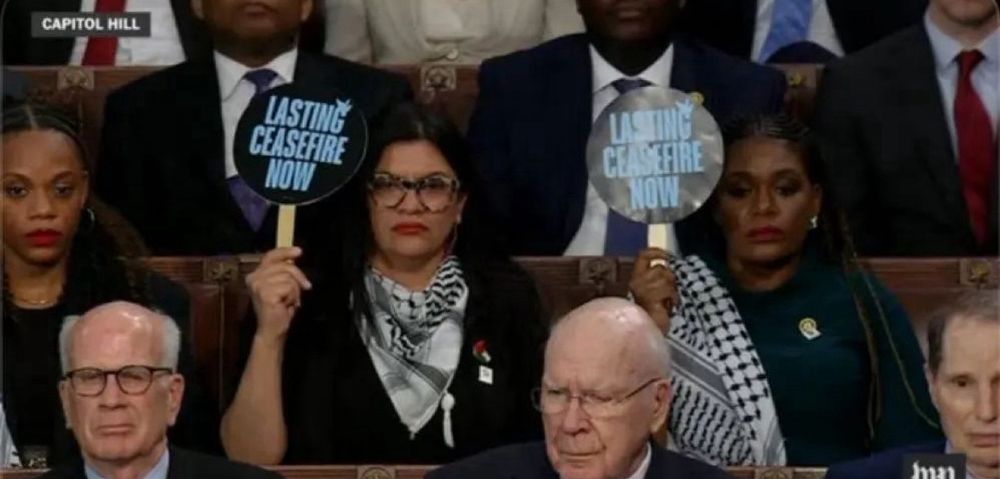 Rashida Tlaib and Cory Bush hold up LASTING CEASEFIRE NOW signs during the SotU