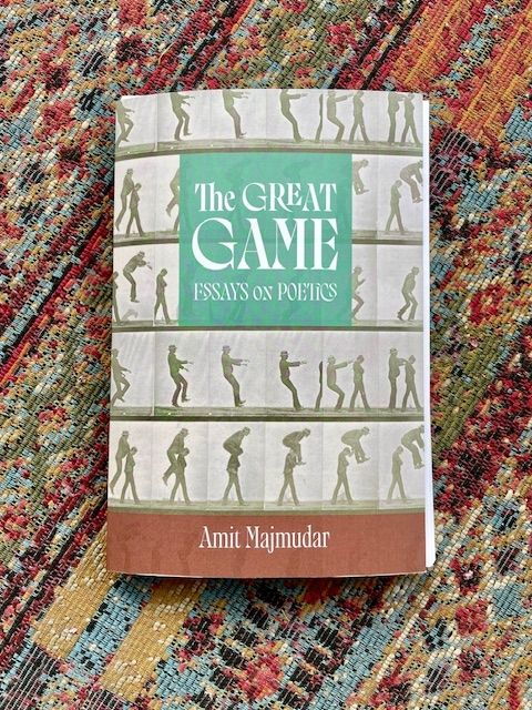 Amit Majmidar's essay collection, The Great Game (cover image features a series of human silhouettes) rests on a carpeted background. 