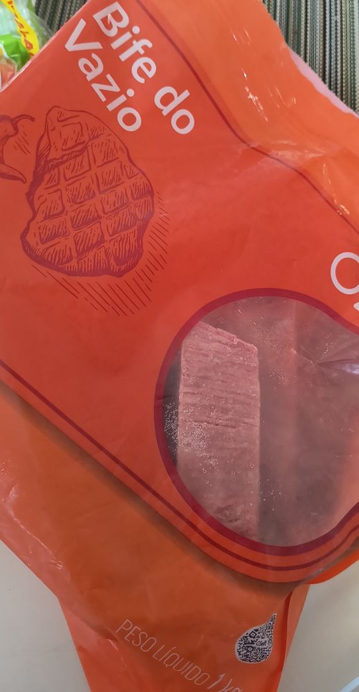 foto de um pacote laranja escrito "bife de vazio" com um pedaço transparente onde é possível ver a carne dentro do pacote