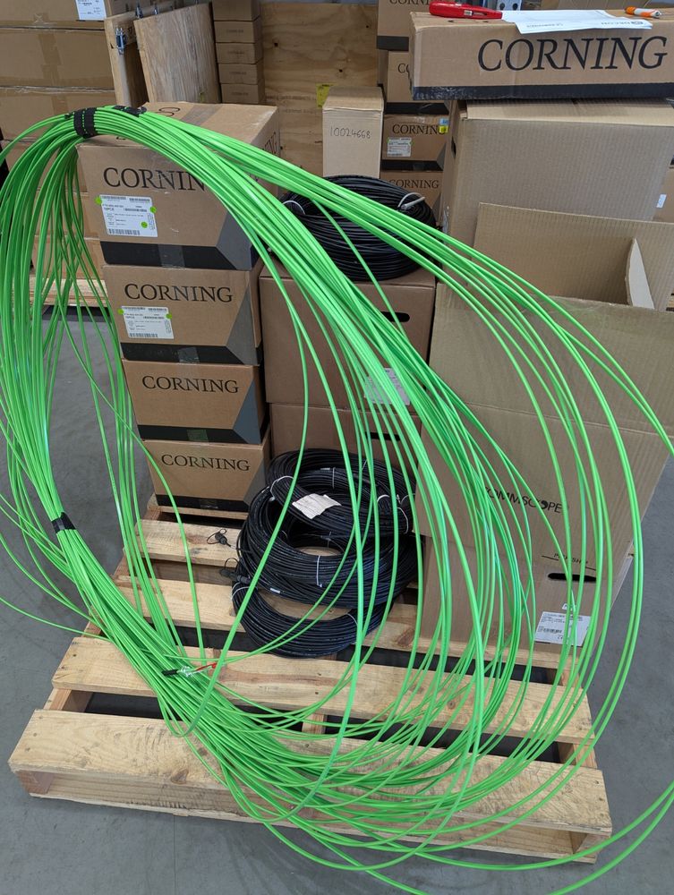A photo of a bunch of boxes and reels of fibre optic cable on a pallet