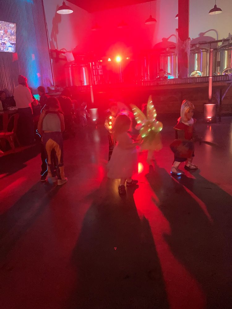 A group of children in costumes on a dance floor with a powerful red light