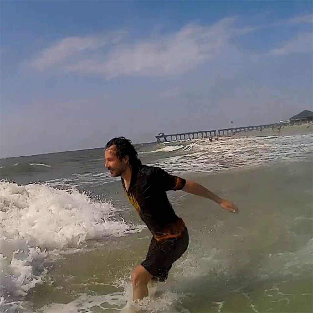 a man in a wet shirt is riding a wave in the ocean