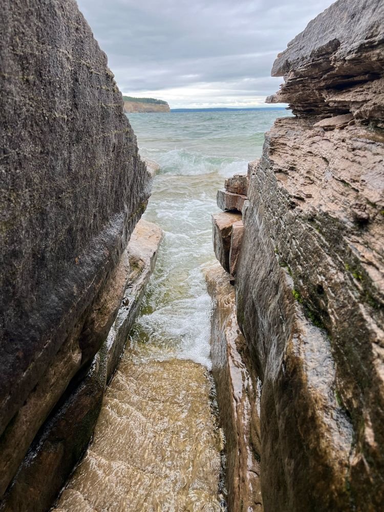 A forced perspective shot to make a thin break in the rocks appear larger than they are. Cliffsides of Pictured Rocks visible on the horizon.