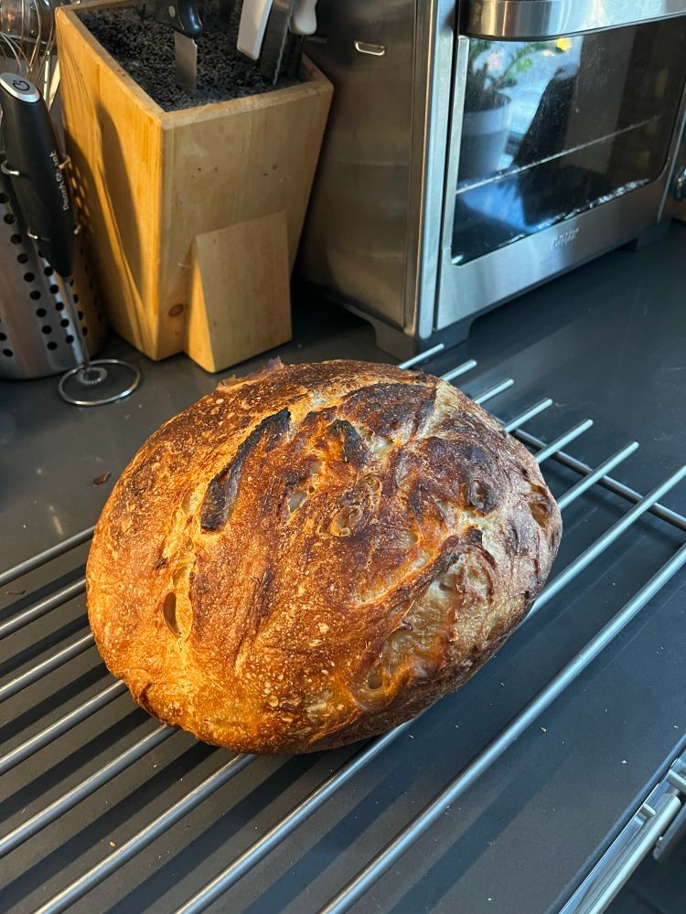 Oval golden brown loaf of bread on a cooling rack