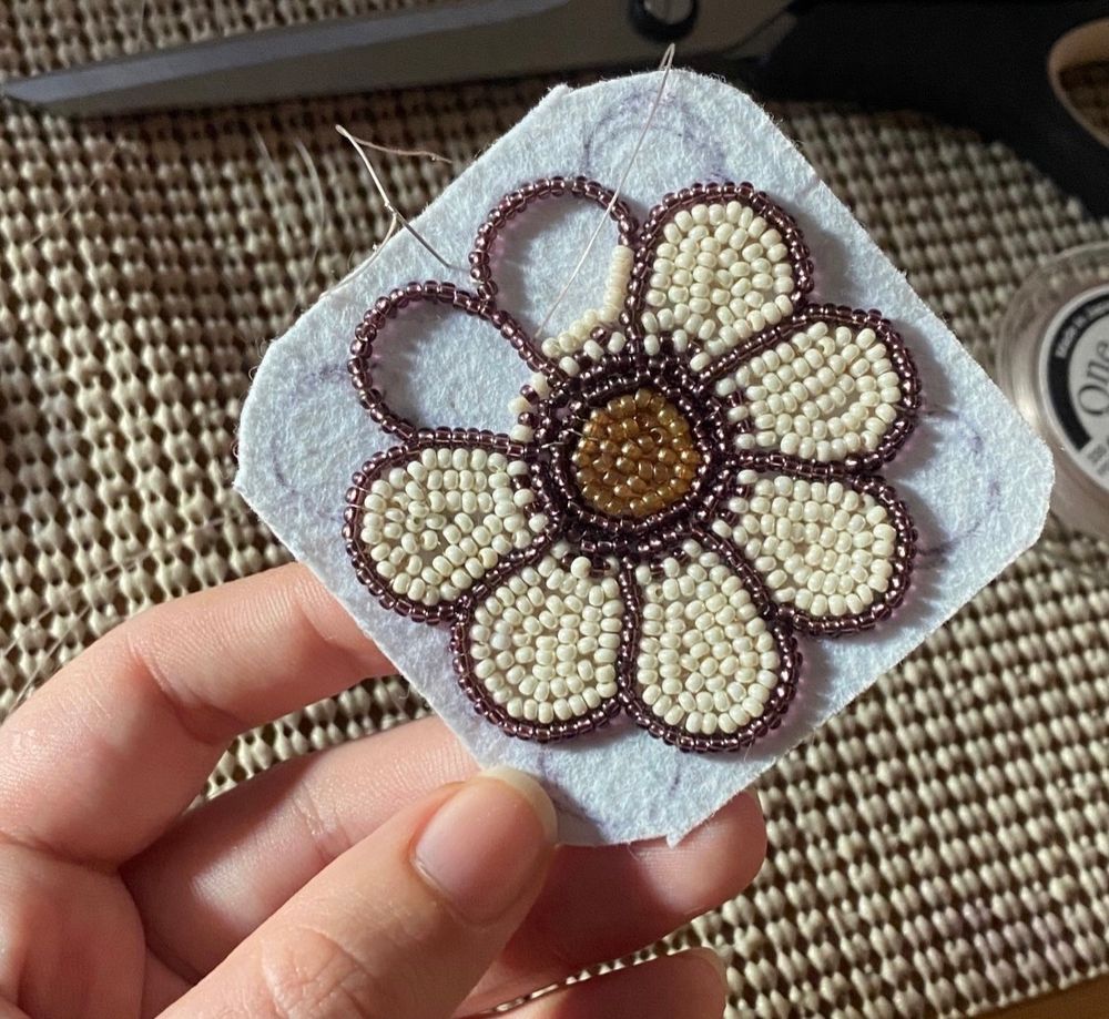 a progress photo of my very first beaded flower. it’s white with 8 petals, two left unfinished. (I never finished this because I wasn’t happy with how lumpy it felt; I didn’t count my beads.)