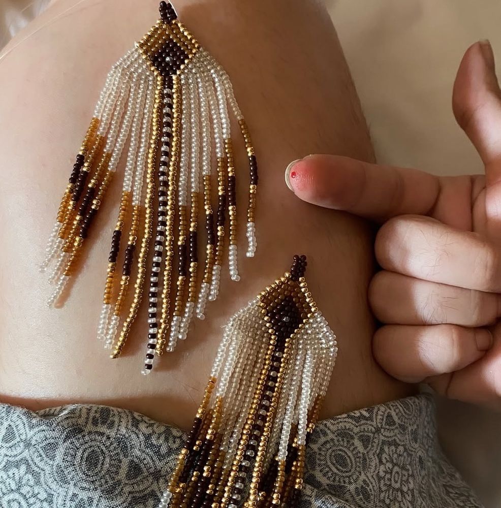 a pair of beaded earrings sitting on my lap. pictured is my right pointer finger that I accidentally pricked with my beading needle.