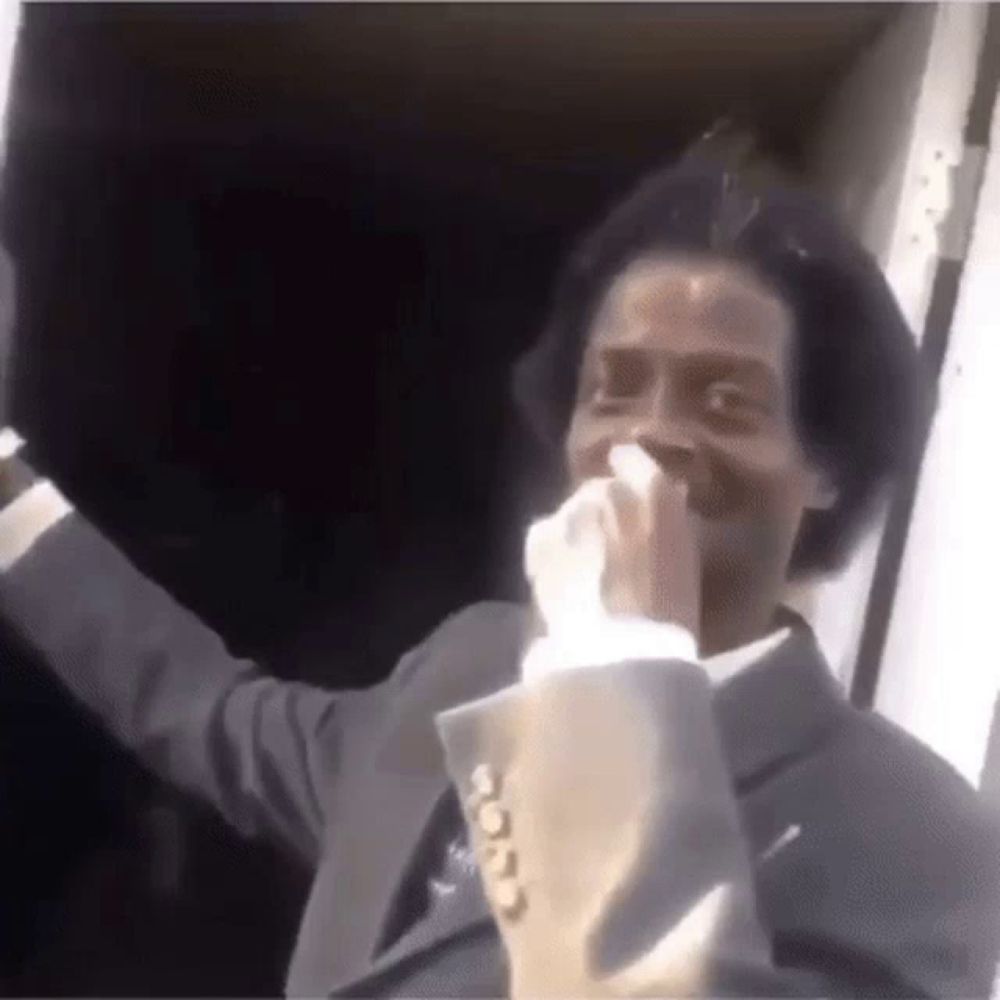 a man in a suit is blowing his nose with a tissue while standing in front of a door .