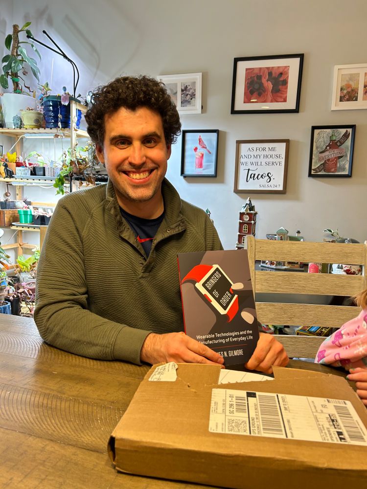 James sitting with his copy of his book, Bringers of Order
