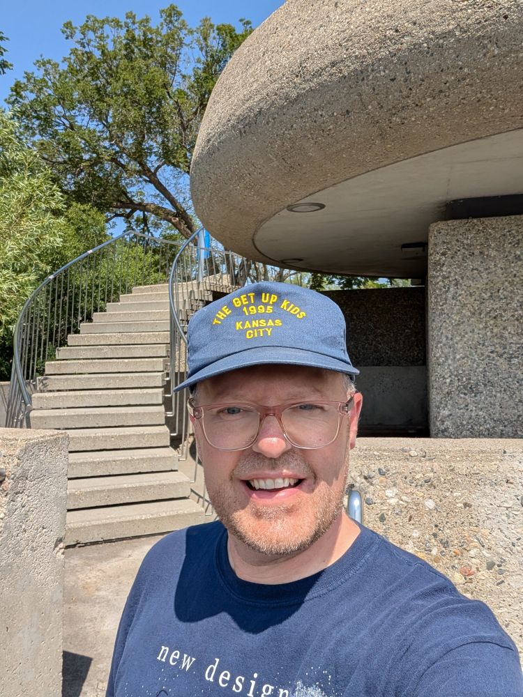 Concrete staircase and viewing space, man in hat smiling in foreground 