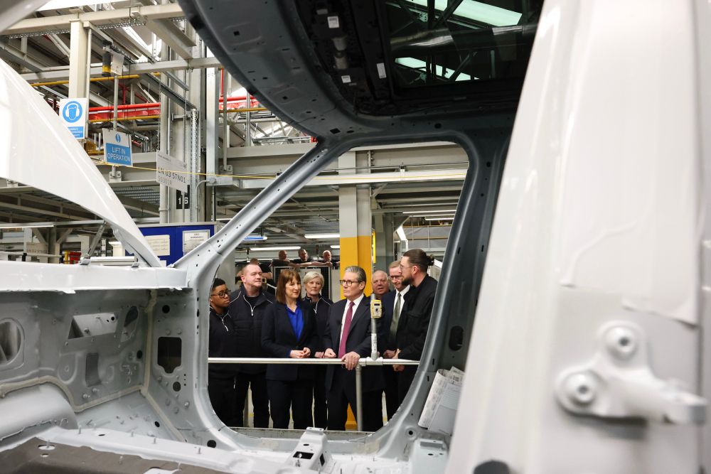 Keir Starmer and Rachel Reeves look at a car in production at Jaguar Land Rover, alongside workers and senior managers.