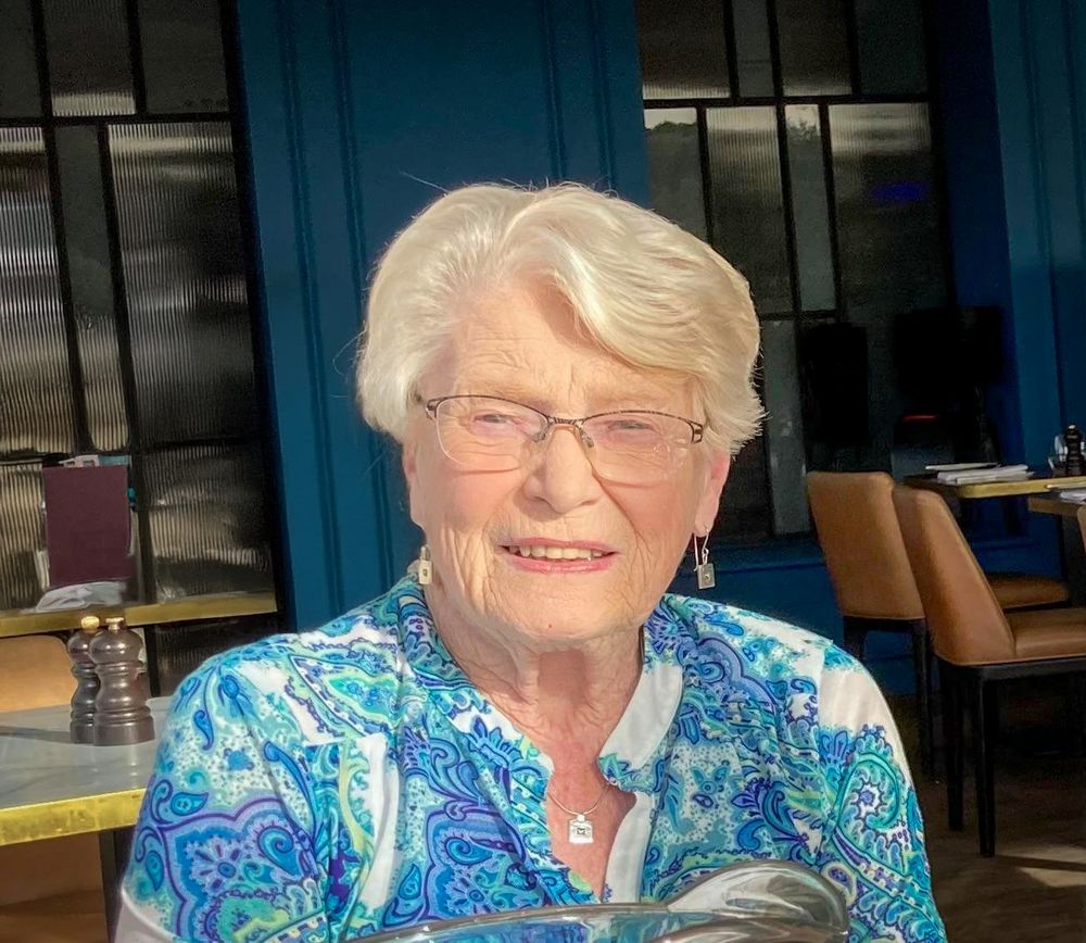 A person looking into a camera sat at a restaurant. 