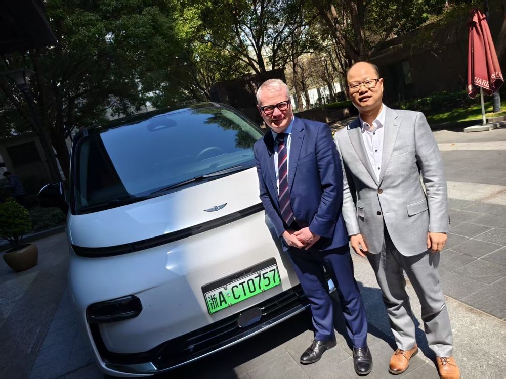 Two people stood next to an electric car in China.