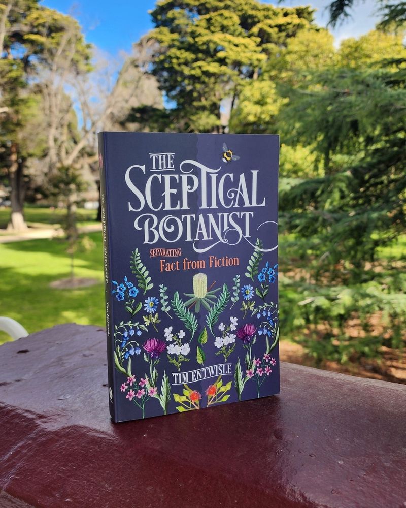 The book 'The Sceptical Botanist: Separating Facts from Fiction' in a park setting. The cover features a pattern of beautiful botanical illustrations.