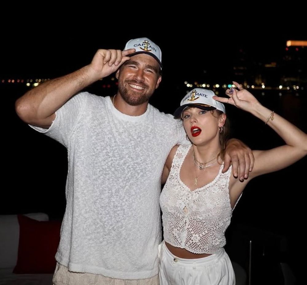 Taylor Swift and Travis Kelce both wearing white outfits and matching boating hats 