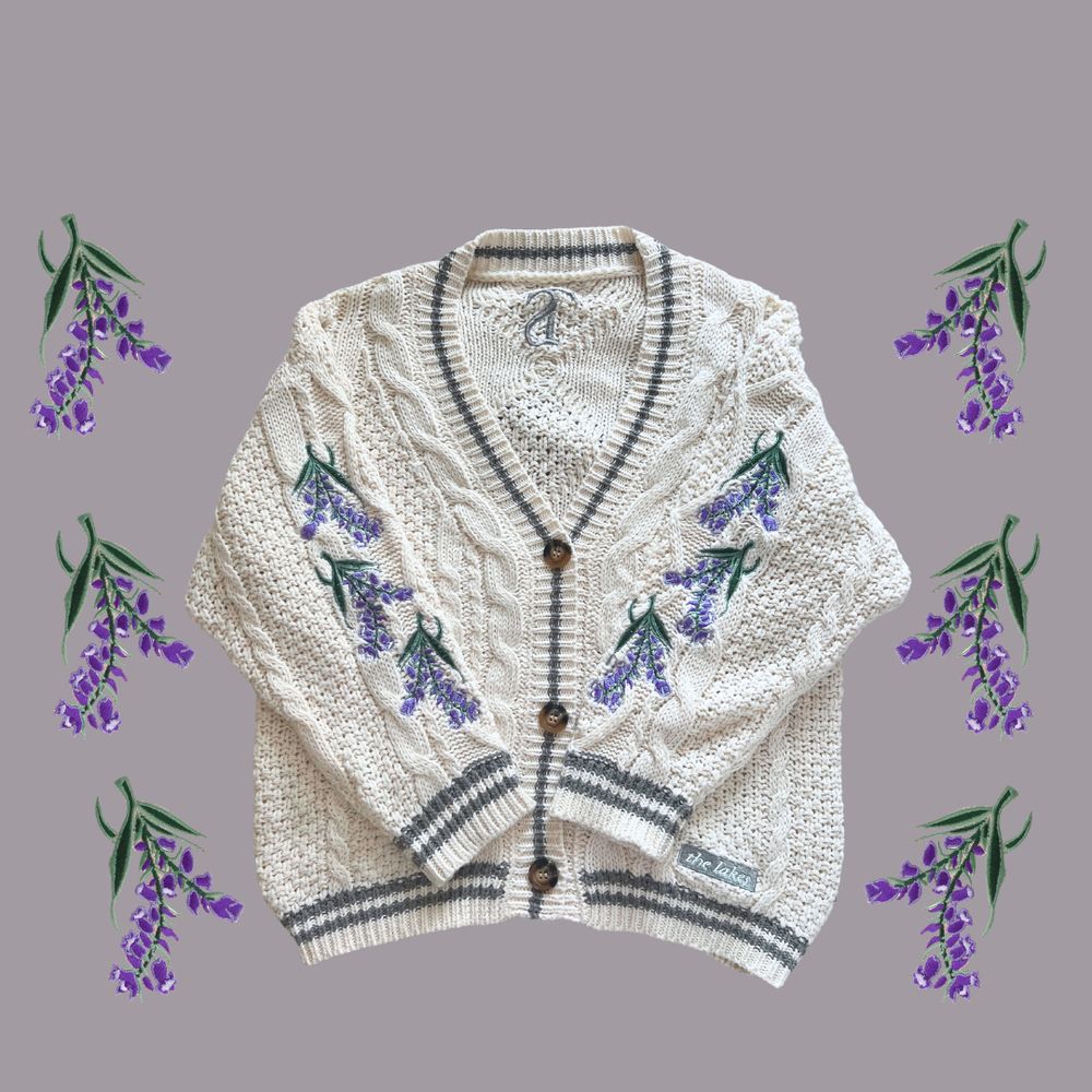 white cardigan with grey trim and purple flowers on the sleeves, inspired by taylor swift’s song: the lakes.