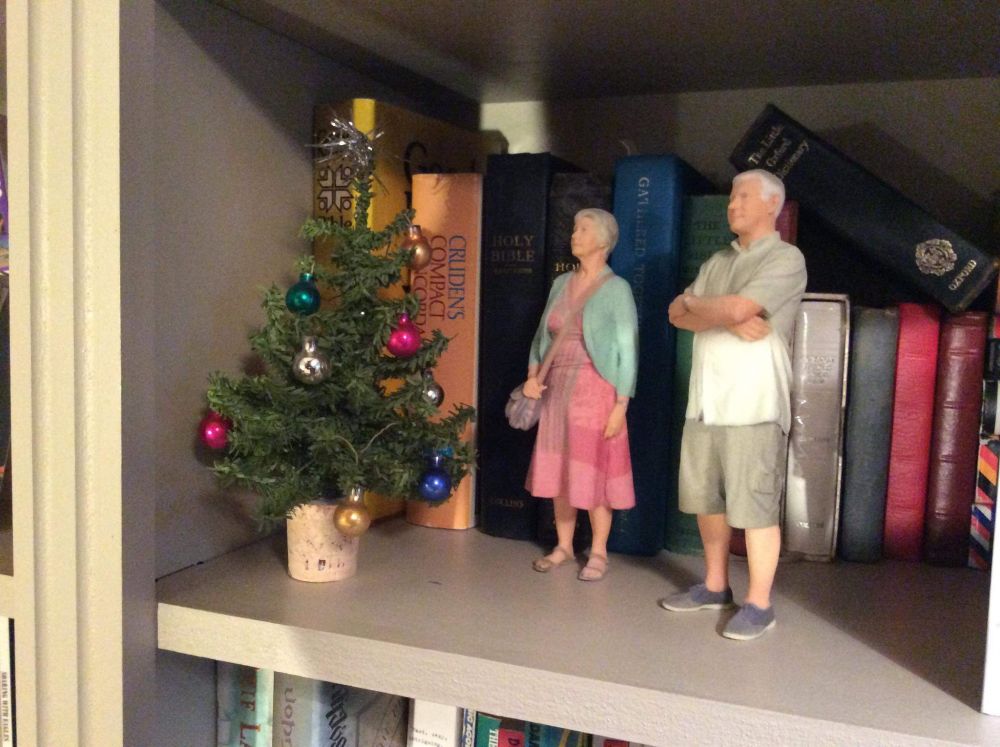 Small models of my mum & dad, 3D printed and about the same height as a book. They are uncannily realistic. Next to them, the a christmas tree spruce with a cork for a bucket / stand, and tiny baubles. Unclear where she got the tiny baubles. 