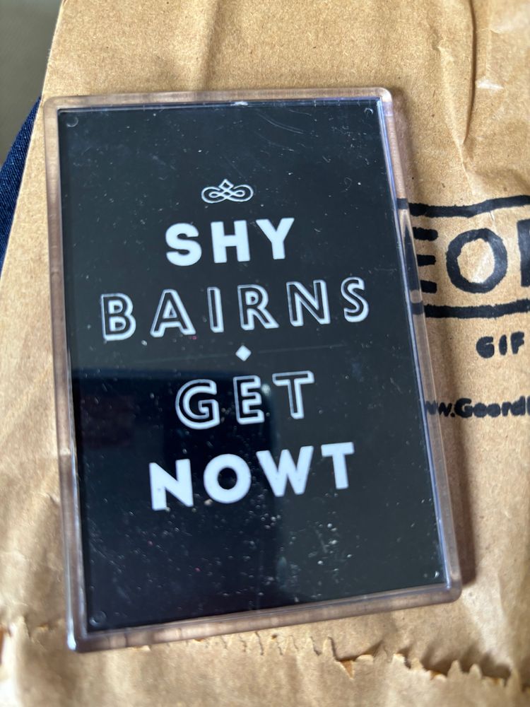 A photograph of a fridge magnet bearing the phrase “shy bairns get nowt”. 
