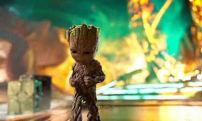 a baby groot from the movie guardians of the galaxy is standing in front of a green background .