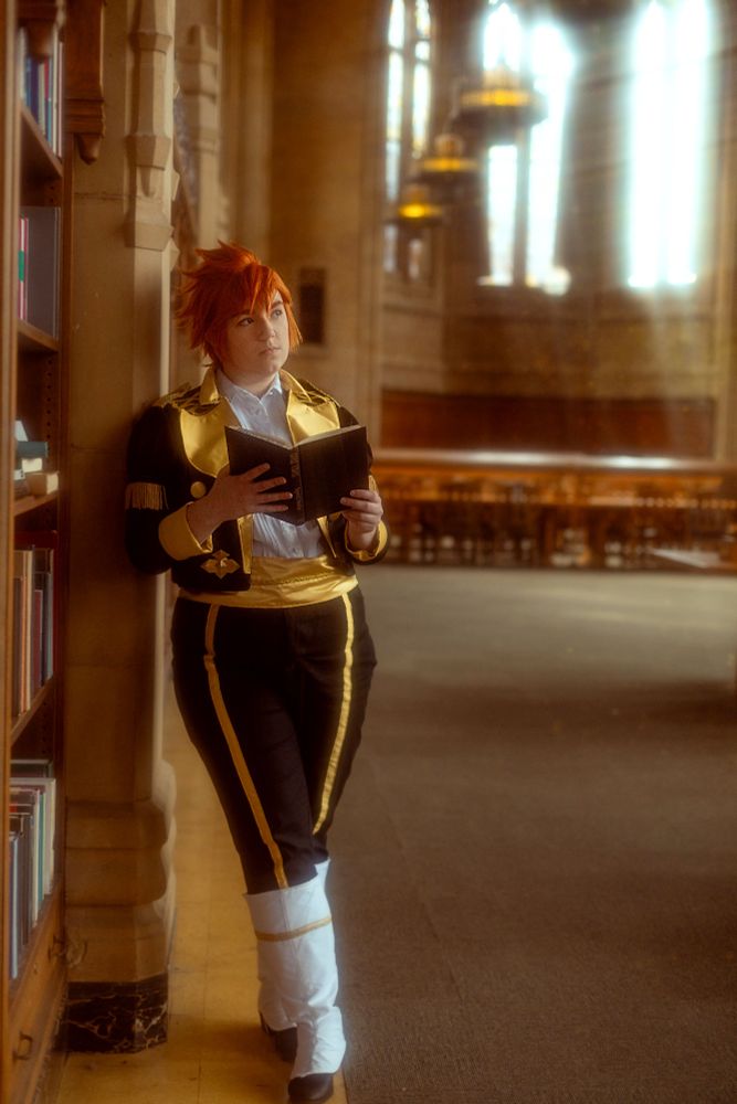 A cosplay of Sylvain Jose Gautier in the reading room at the Suzzallo and Allen Libraries, leaning against the wall and holding a book. The light is warm, and the room is otherwise empty, peaceful.
