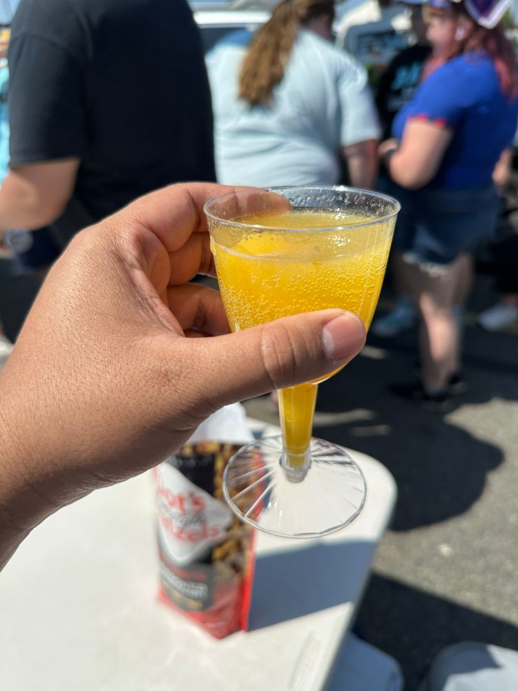 Me holding a cup of an orange colored cocktail 