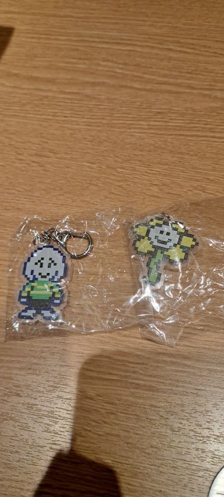 Photo of two keychains with undertale's asriel and flowey, still in plastic wrap 