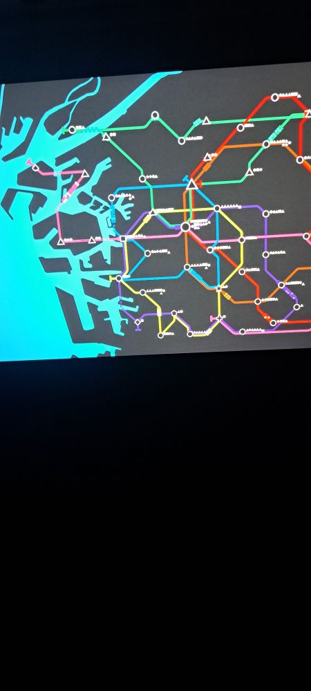Blurry photo of mini metro being played on the back of an airplane seat