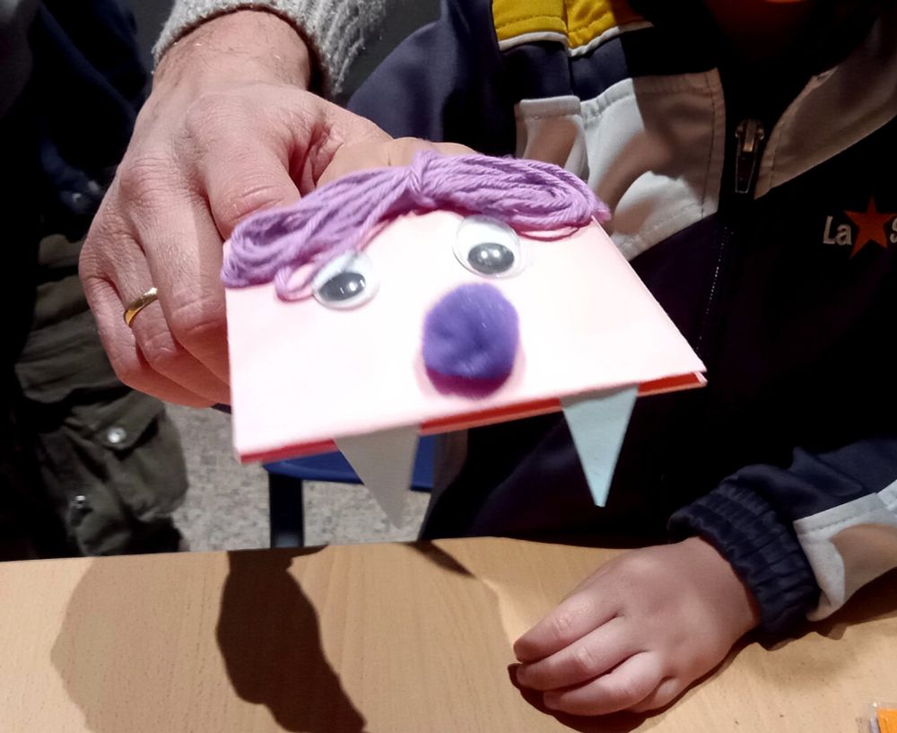 Un vampiro rosa con pelo y nariz morados y grandes y amenazantes colmillos.