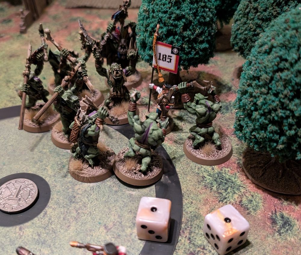 A single Guard standard bearer surrounded by Orks. In the foreground you can see two dice showing two 1s.