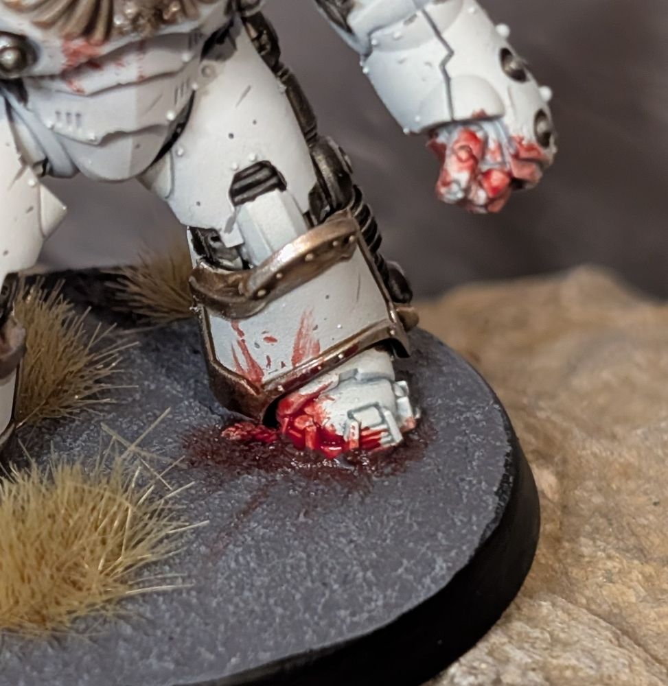 A close up of a huge armoured foot, spattered with blood as if it's just stomped some poor unfortunate.