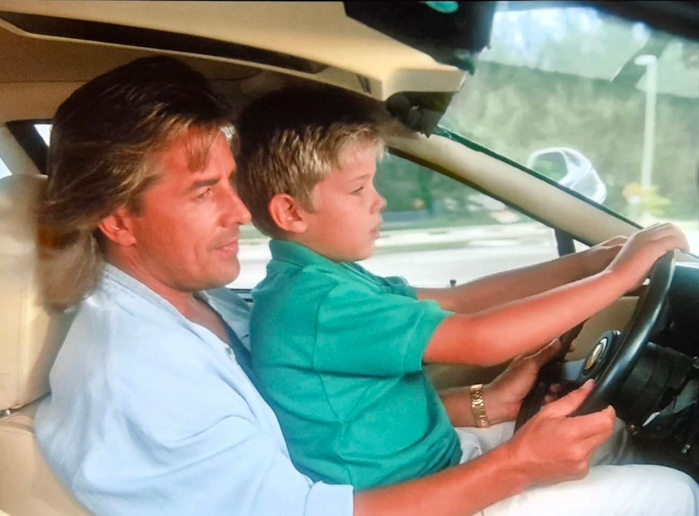 Isä ja poika yrittävät bondata Ferrarin ratissa.