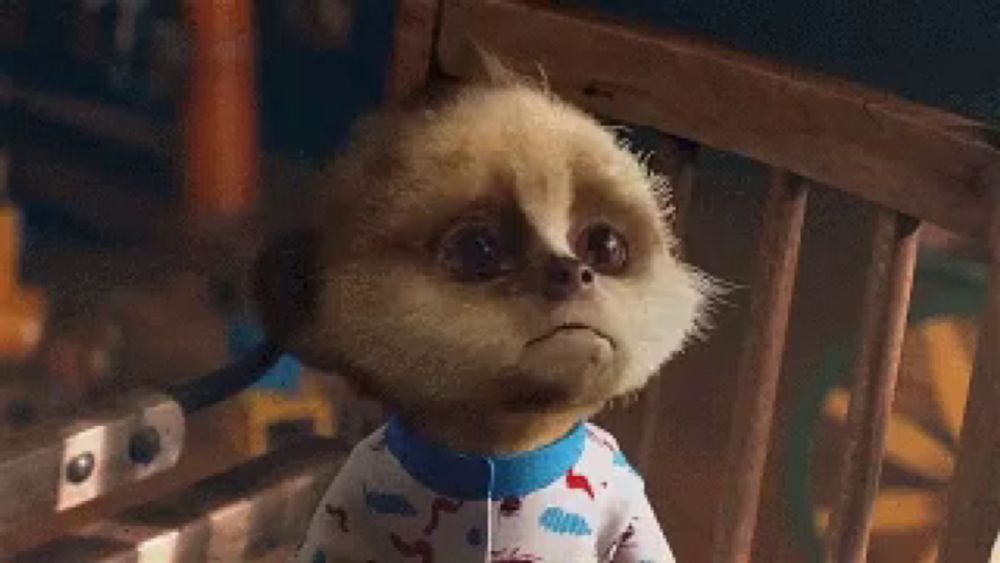 a meerkat wearing pajamas is sitting in a chair and making a sad face