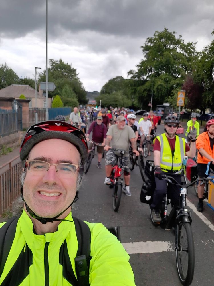 Selfie of a cyclist on a road with lots of bikes behind him.