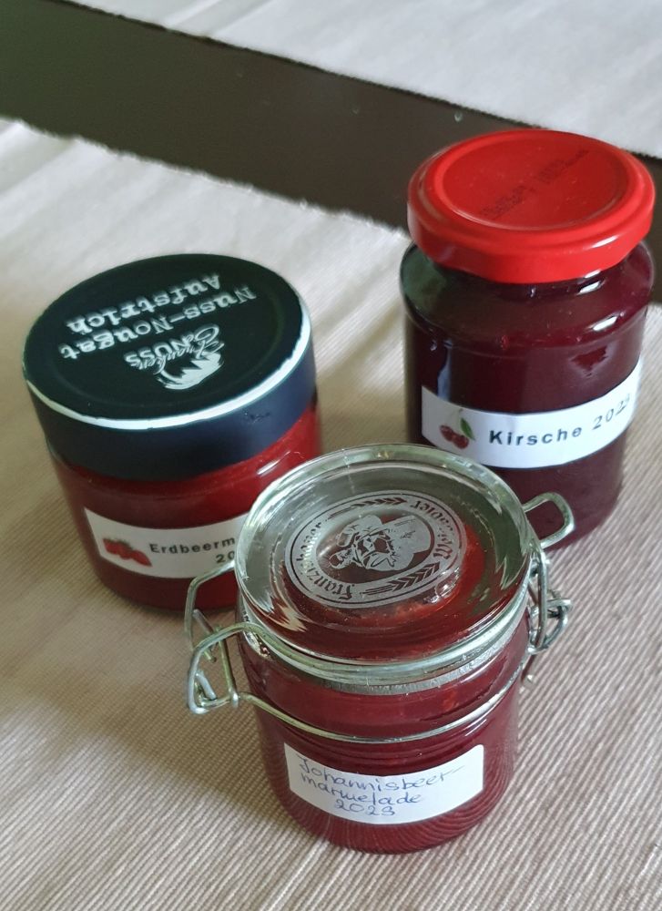 Drei Einmachgläser, gefüllt mit unterschiedlichen selbstgemachten Marmeladen.