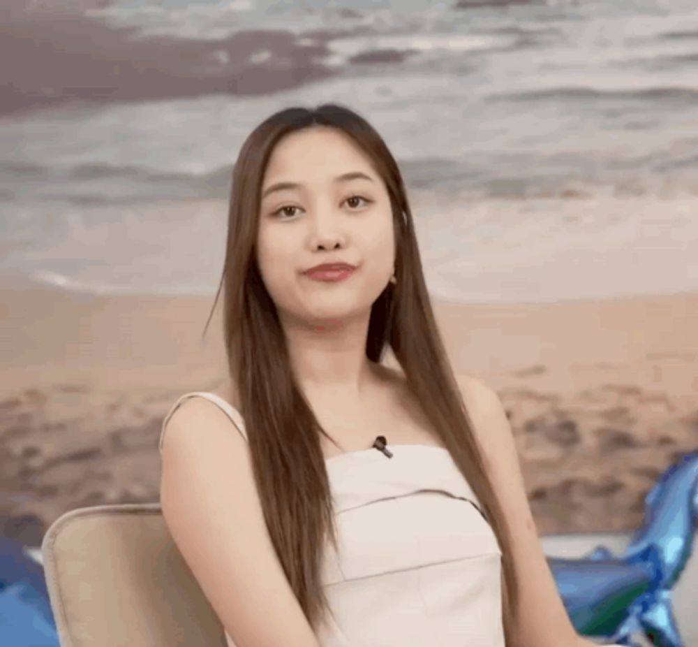 a woman with long hair is sitting in front of a painting of the ocean