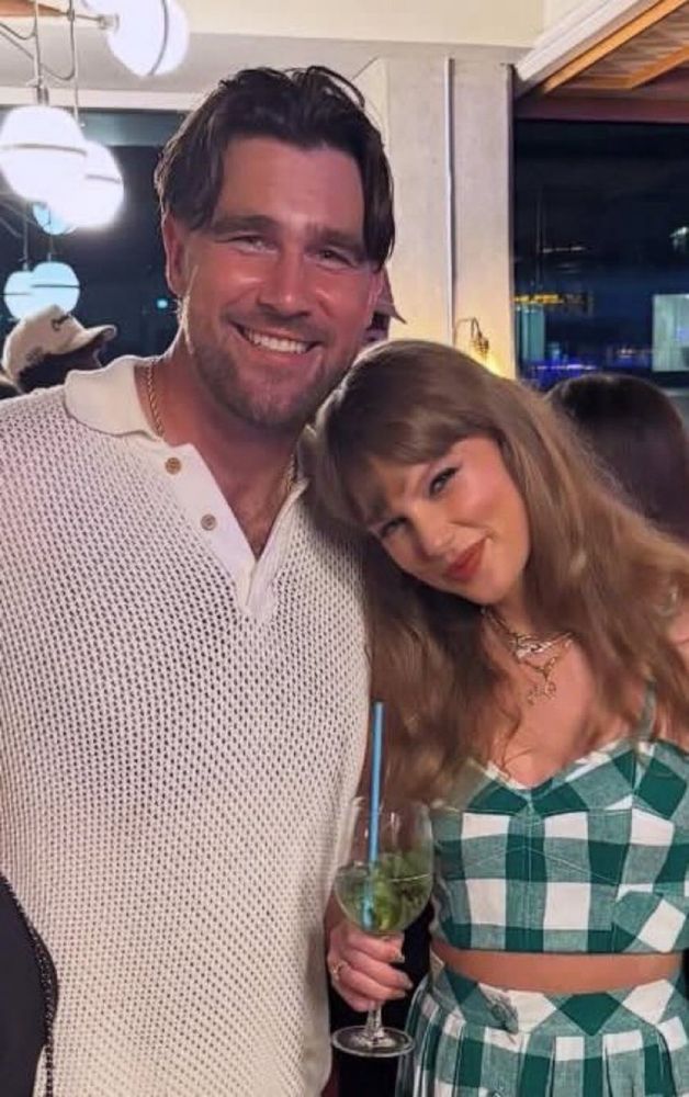 travis kelce wearing a white top with taylor swift wearing a green and white checkered outfit 