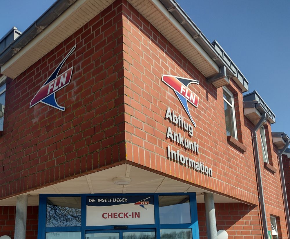 ein rotes backsteingebäude,darauf der schriftzug,abflug,ankunft, information 
der inselflieger,von hier aus,kann man nach wangerooge fliegen