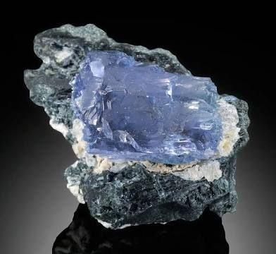 Enclosed in almost a clamshell of its Matrix Rock a beautiful piece of Jeremejevite is seated on a pillow of white. It's a oblong rectangular chunk that is light blue but due to its Optical properties when turned this would likely appear either darker blue or clear
