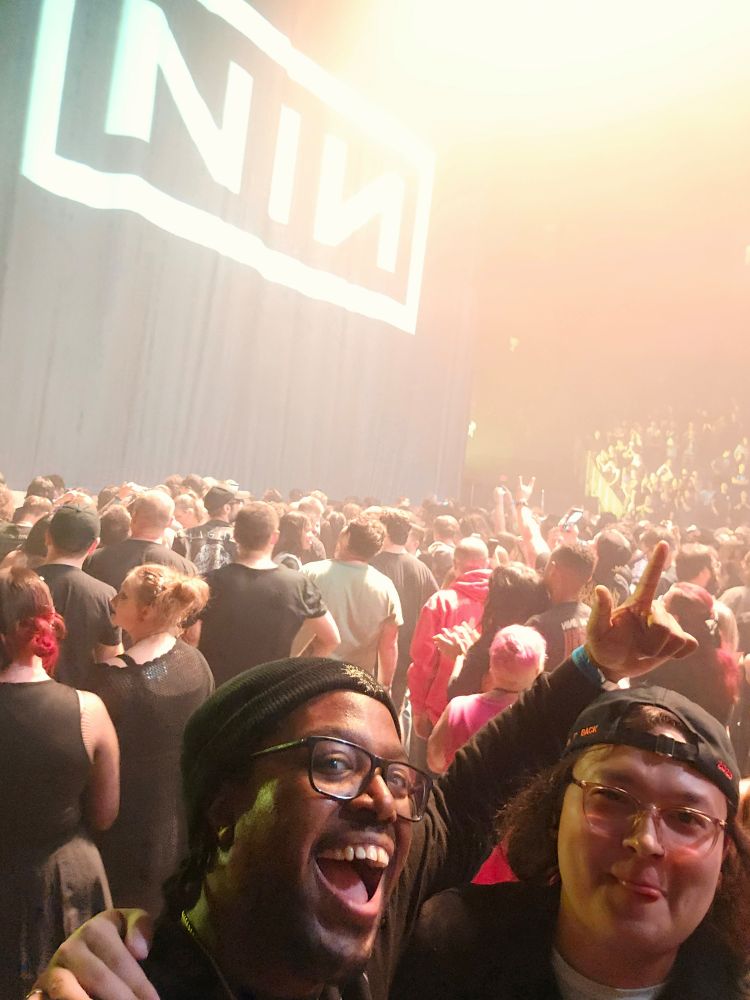 Andy and I under white lights after the show standing next to the curtain with the NIN logo on it