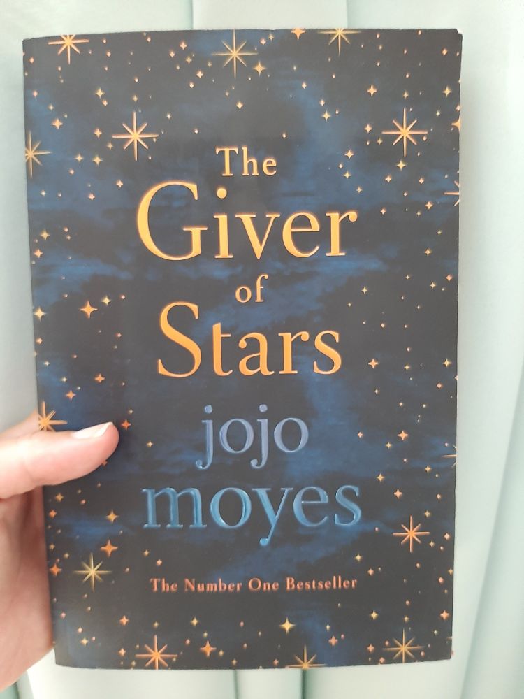 Bookcover of "The Giver of Stars" by Jojo Moyes. The background design is a nightsky with stars.