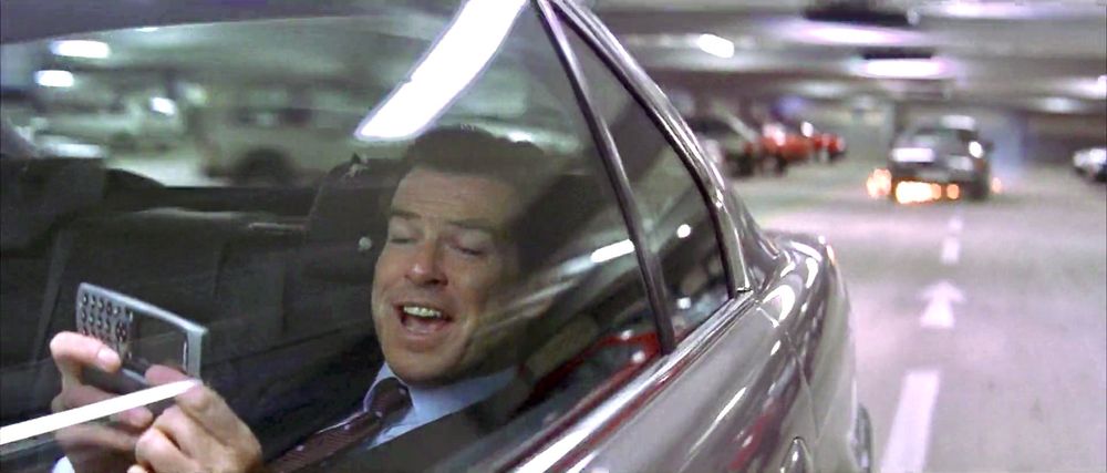 James Bond is playing a game on his dad's Nokia phone while his mom drives them home from the car park of a MaccyD's.