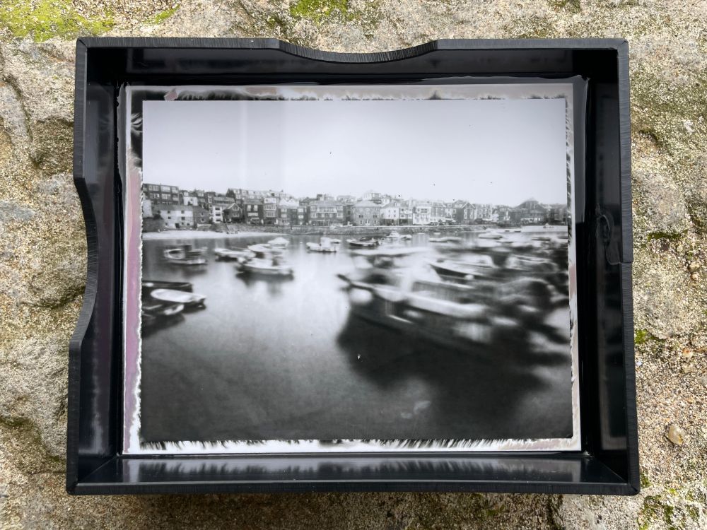 A Pinsta pinhole photograph of fishing boats shot in St. Ives harbour, Cornwall. The images of the boats are blurred, because of the movement of the sea captured by the long exposure.