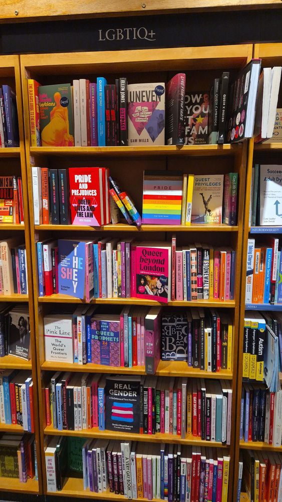 Bücherregal in der Buchhandlung Blackwell’s, beschriftet mit „LGBTIQ+“. Zu sehen sind zahlreiche queere Titel, u.a. „Pride and Prejudices“, „They/Them“, „Queer Beyond London“, „The Pink Line“, „Real Gender“ und viele weitere bunte Buchrücken.