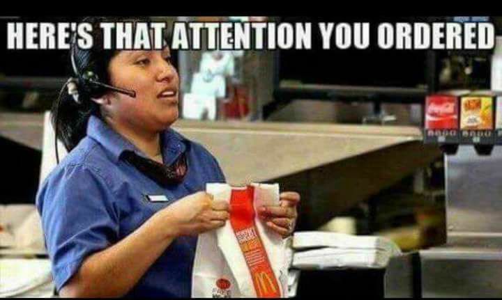 a woman in a McDonald’s uniform and headset holding a McDonald’s bag: “here’s that attention you ordered”