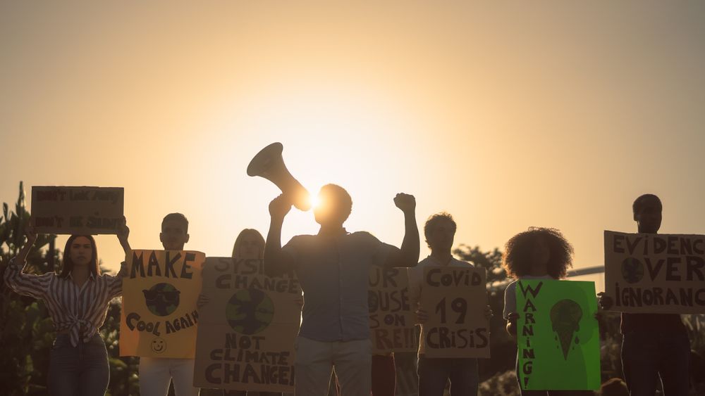 A photo of protesters, shown in silhouette, protesting against climate change.